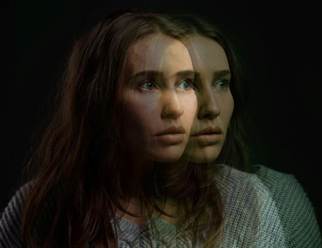 Young woman sitting alone and looking distressed while using a digital device