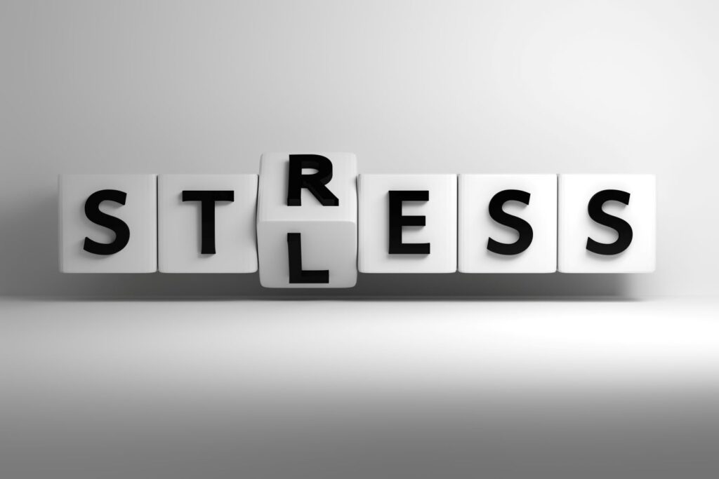 Blocks forming the word stress with one block flipping to less stress, symbolizing workplace stress reduction through leadership strategies by Ginny Estupinian, PhD